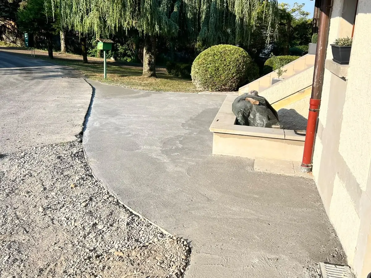 Allée en béton le long d’une maison, avec son caniveau
