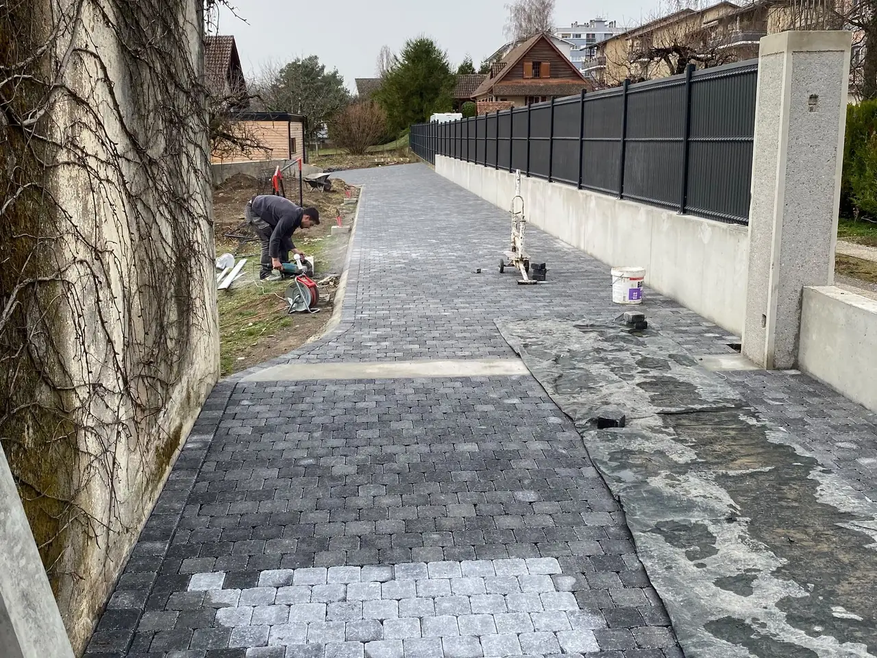 Allée en pavés posée le long d’un mur, la pose continue au fond