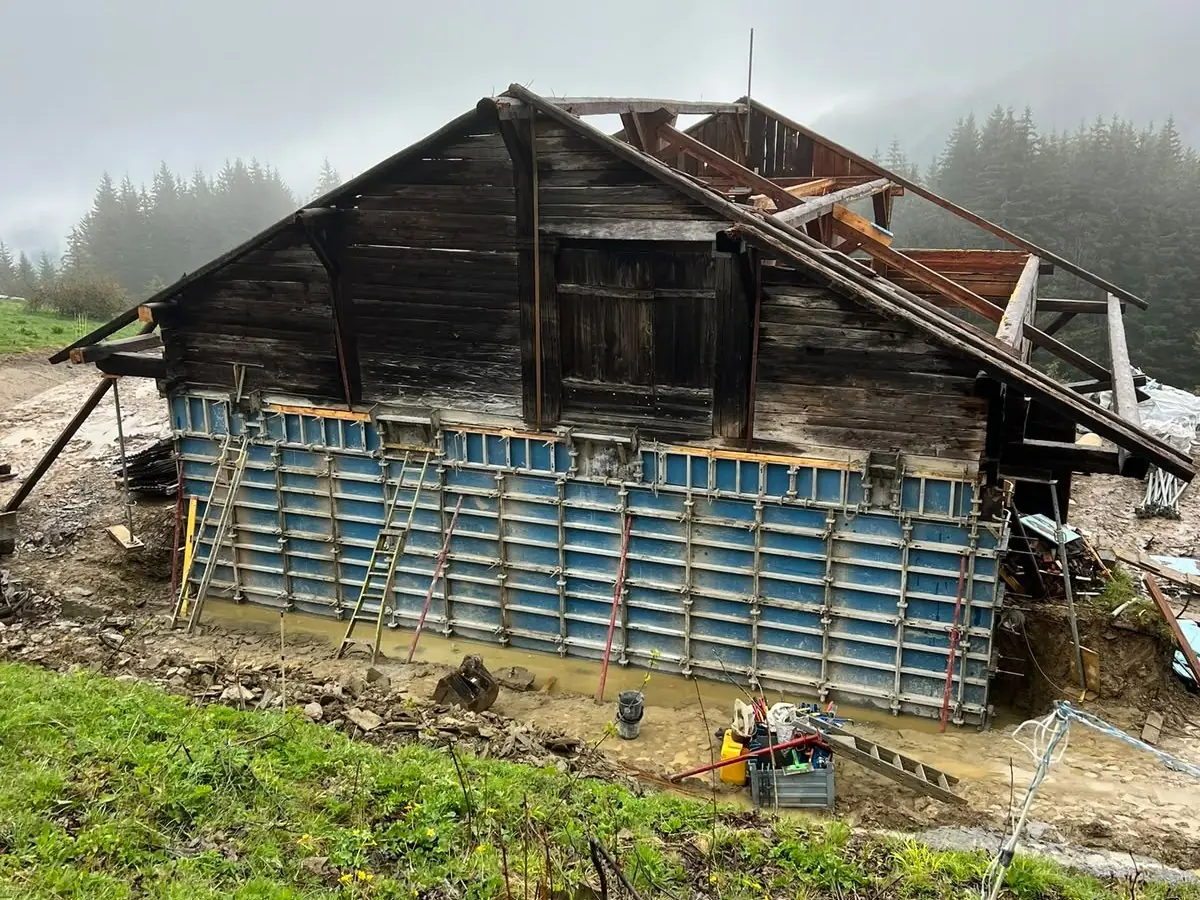 Banches montées le long d’un vieux chalet en bois pour couler son soubassement en béton