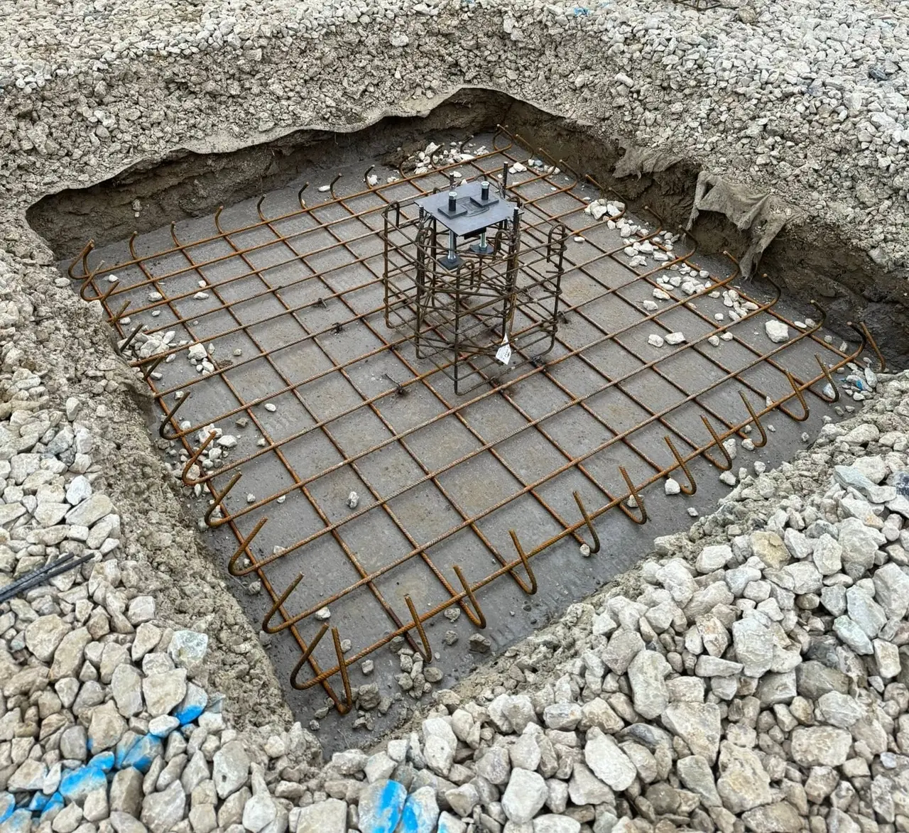 Semelle isolée prête à couler : nappe d’aciers sur le béton de propreté, cage d’armatures et platine d’ancrage en tête.