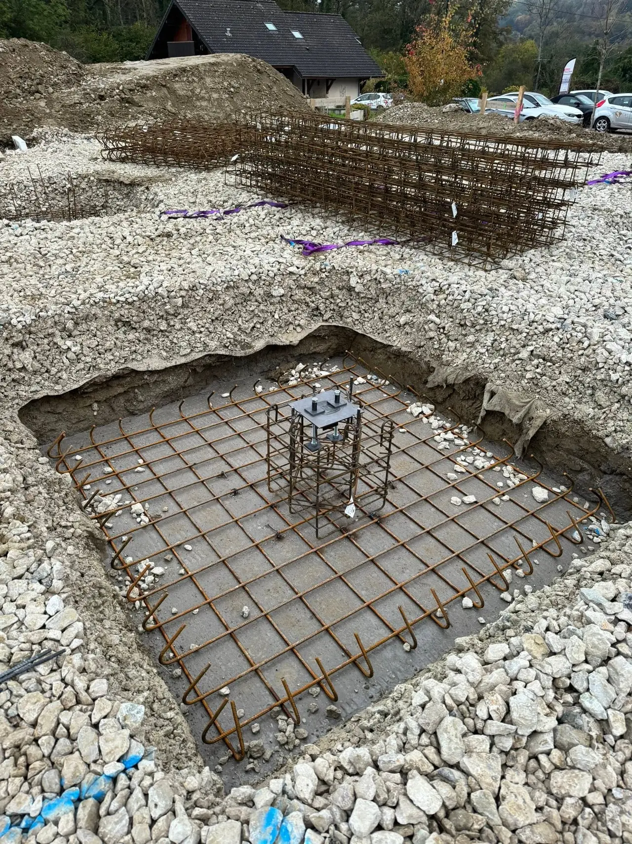 Semelle de fondation ferraillée et platine d'ancrage en attente de scellement.