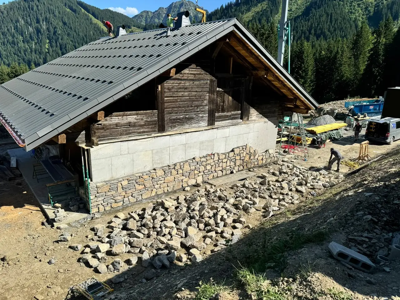 Soubassement en béton d’un chalet habillé de pierre sur sa partie basse, toit refait