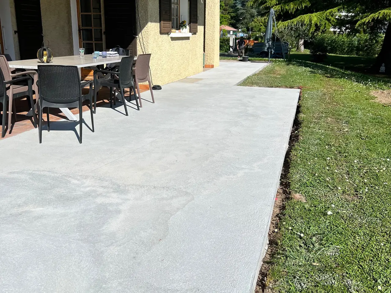 Terrasse en dalle béton devant une maison, sous le balcon